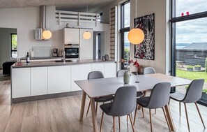 A modern kitchen with a central island, dining table with chairs, pendant lights, and a large window with a view. - Cozy home in Børkop with house sea view (Børkop)
