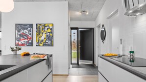 Una cucina moderna con due dipinti astratti, una pianta in vaso e una ciotola di frutta.