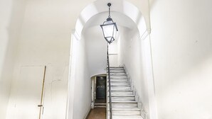 A narrow hallway with a staircase leading to a door at the end. - Coliseum View Diana's House by Rentbeat (Roma)
