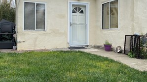 A single-story house with a beige exterior, a white front door, and two windows with shutters. - Lovely house with WiFi in charming Alameda (Alameda)
