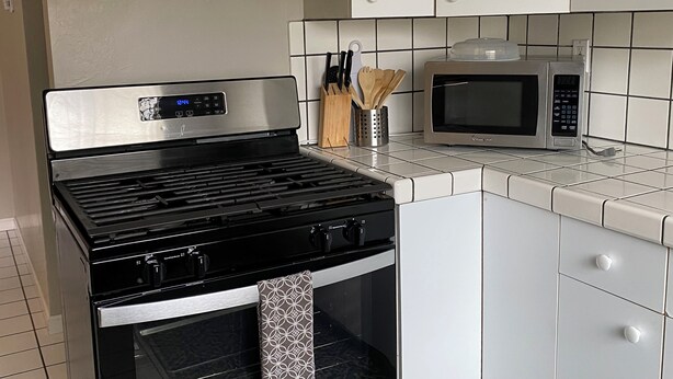 A kitchen with a stainless steel stove, a microwave, and white cabinets. - Lovely house with WiFi in charming Alameda (Alameda)