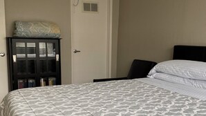 A neatly made bed with a patterned bedspread, a black headboard, and a small cabinet with books. - Lovely house with WiFi in charming Alameda (Alameda)