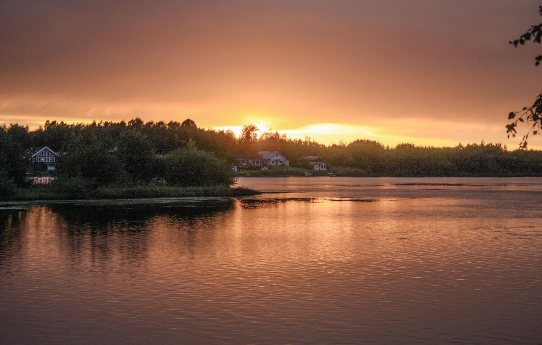 A serene lakeside view with a house and a boat docked on the shore.