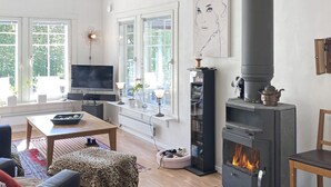 A cozy living room with a fireplace, a television, and a bookshelf.