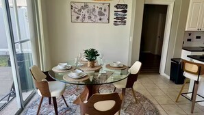 A dining area with a glass table surrounded by chairs, a woven placemat, and a small potted plant. - Dream Villa W/ Pool Near Disney3 Bed 2 Bath, (Davenport)