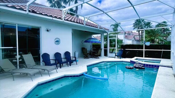 An indoor swimming pool with clear blue water, surrounded by lounge chairs and a covered patio area. - Dream Villa W/ Pool Near Disney3 Bed 2 Bath, (Davenport)