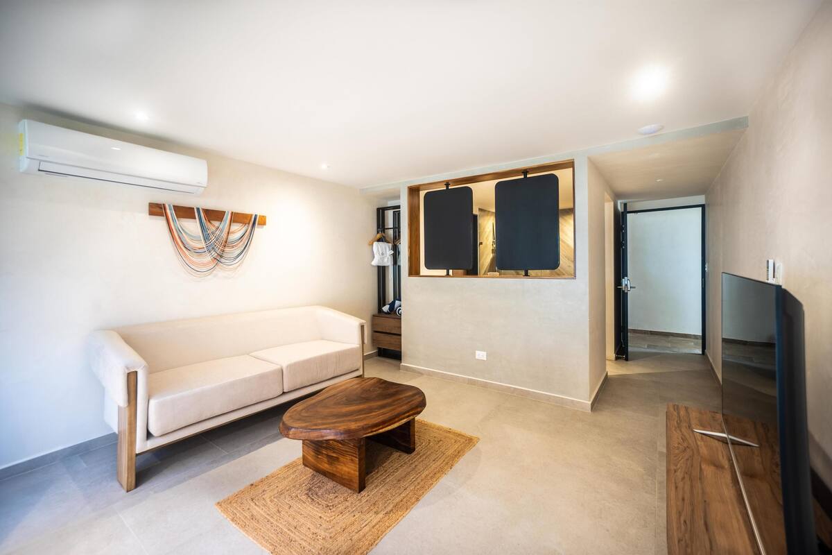 A modern living room with a sofa, coffee table, TV, and artwork on the wall.