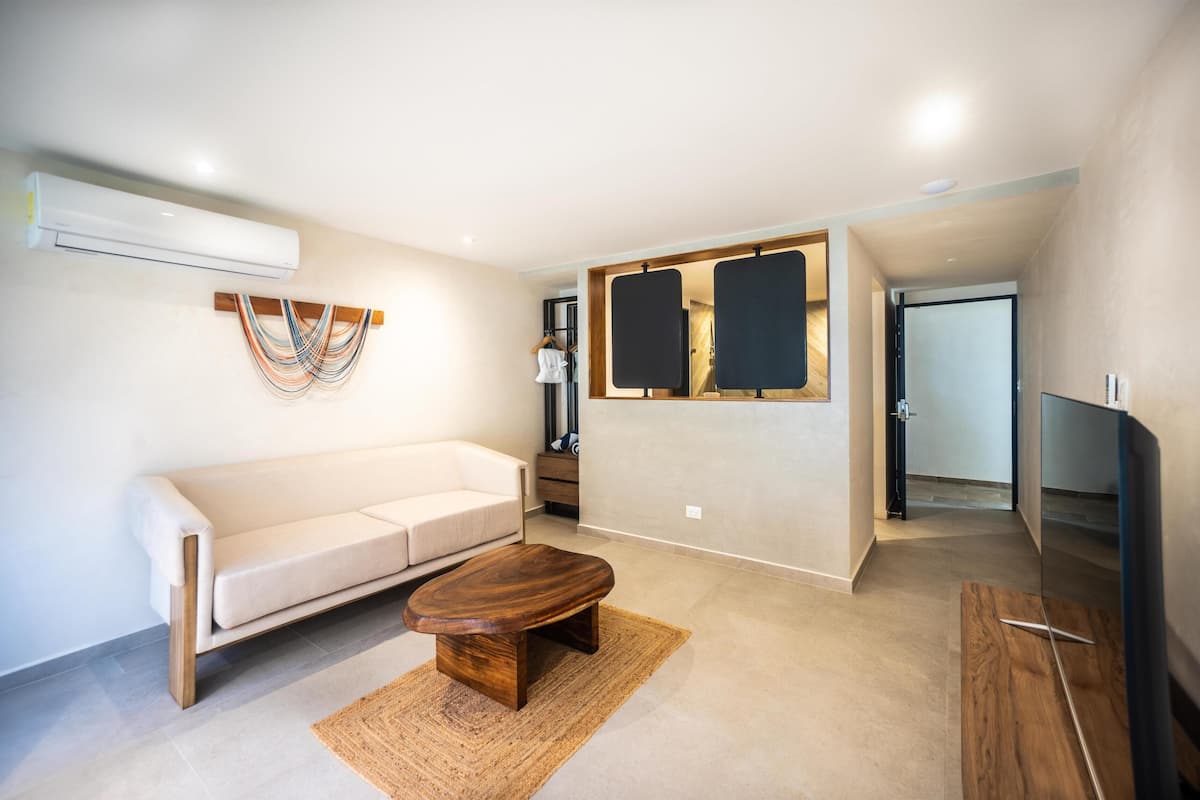 A modern living room with a sofa, coffee table, TV, and artwork on the wall.