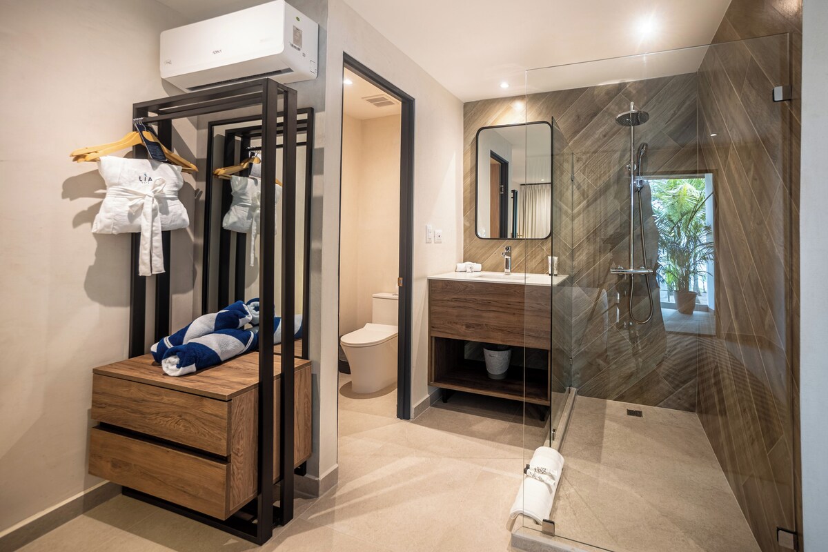 A modern bathroom with a wooden vanity, a glass shower enclosure, and a hanging robe rack.