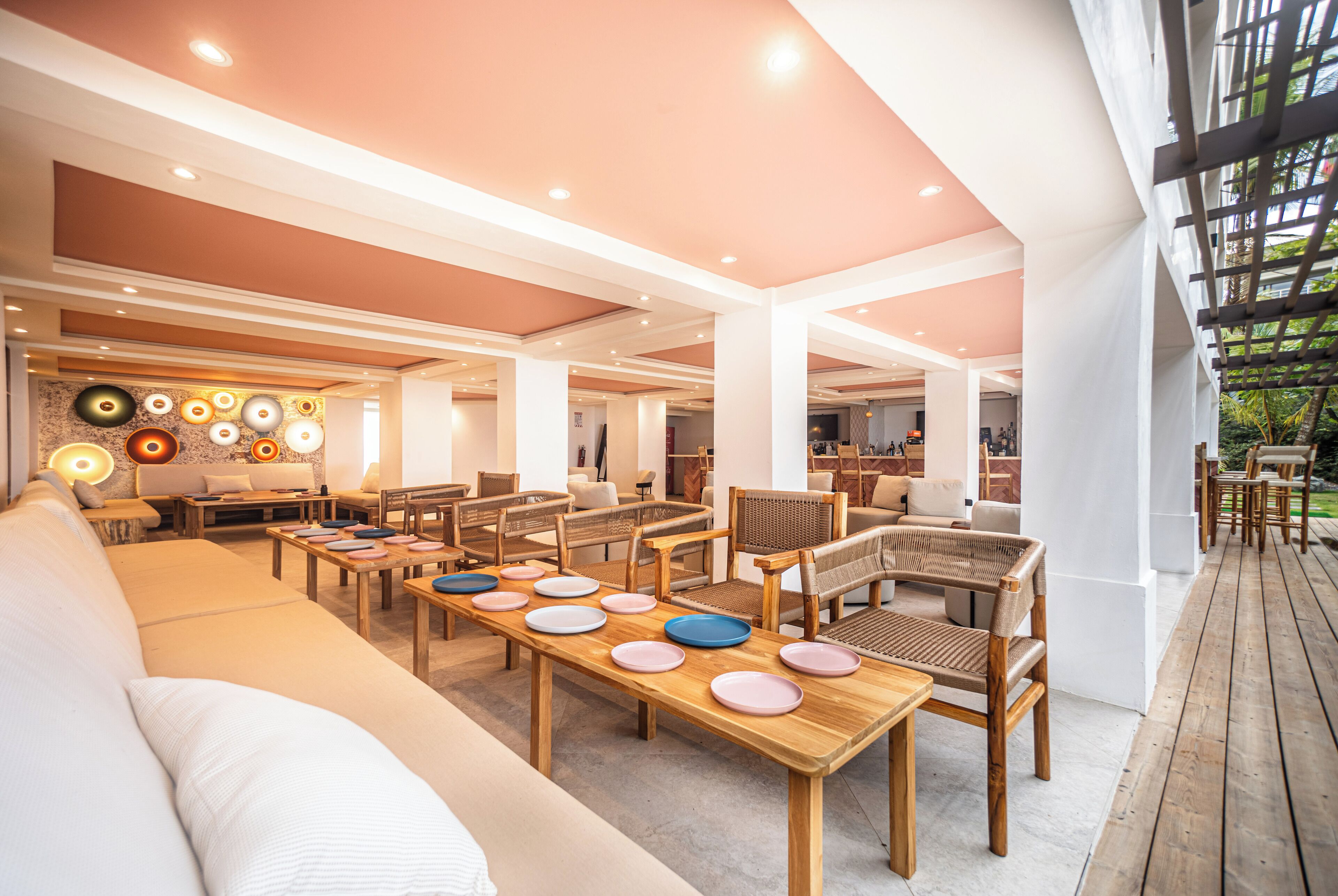A spacious indoor area with multiple seating arrangements, including sofas and tables, and a wooden deck area.