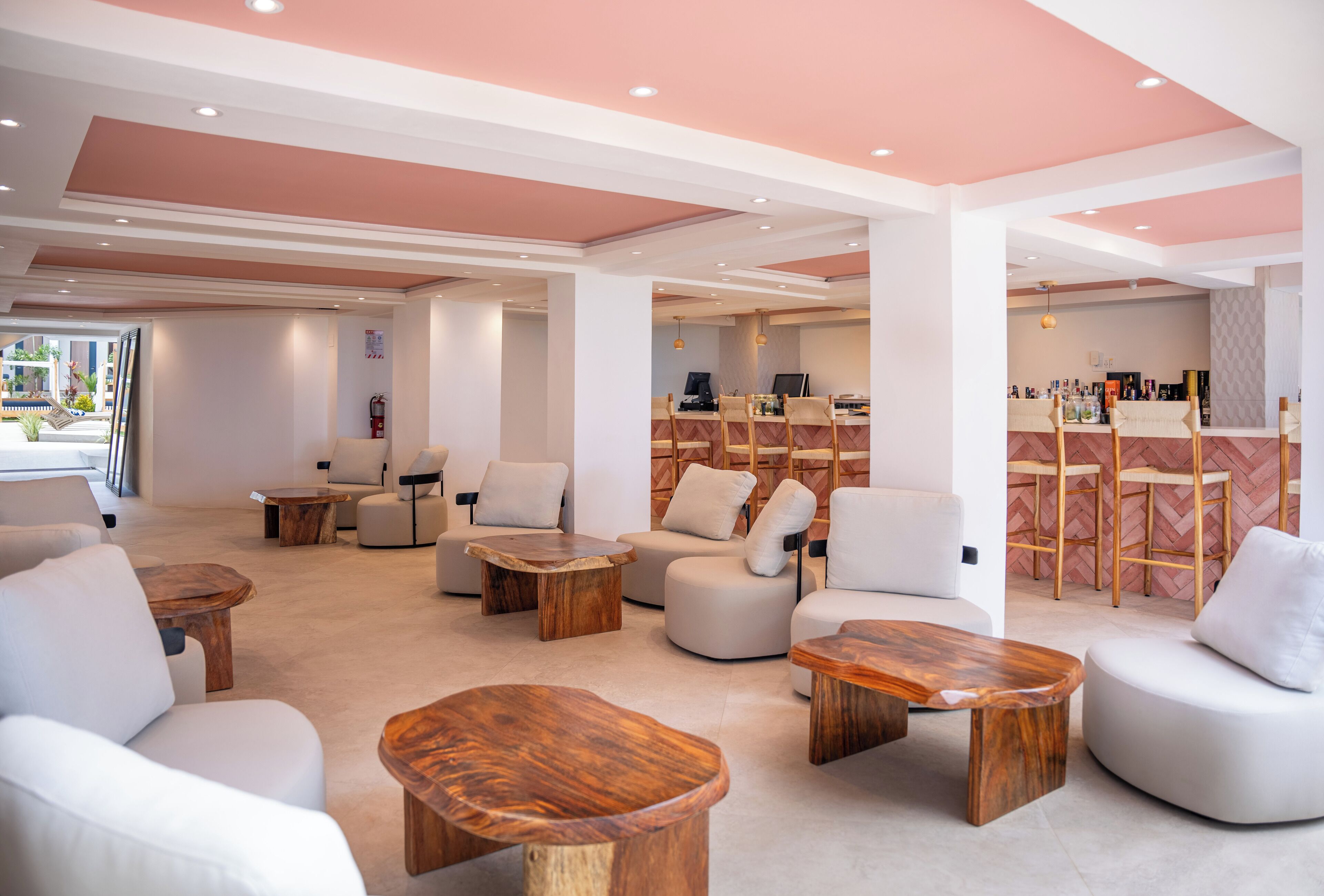 A modern lounge area with white sofas, wooden coffee tables, and a herringbone-patterned wall.