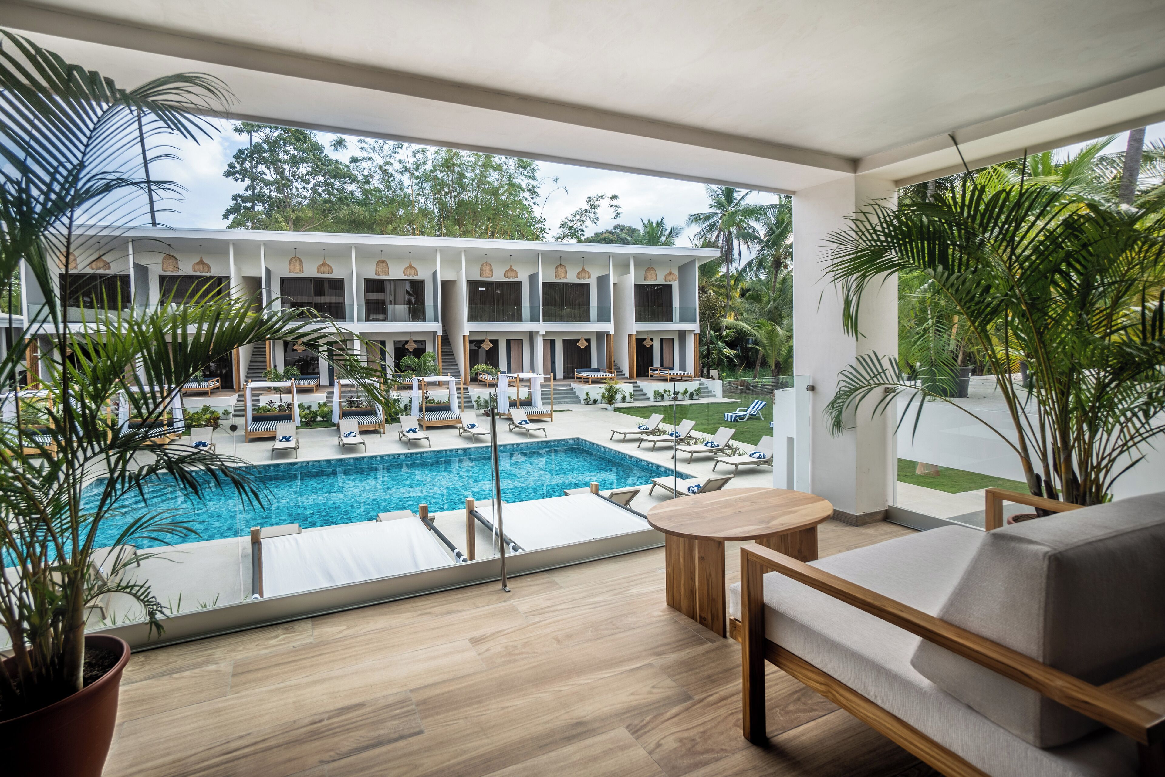 A modern hotel with a pool area, outdoor seating, and lush greenery.