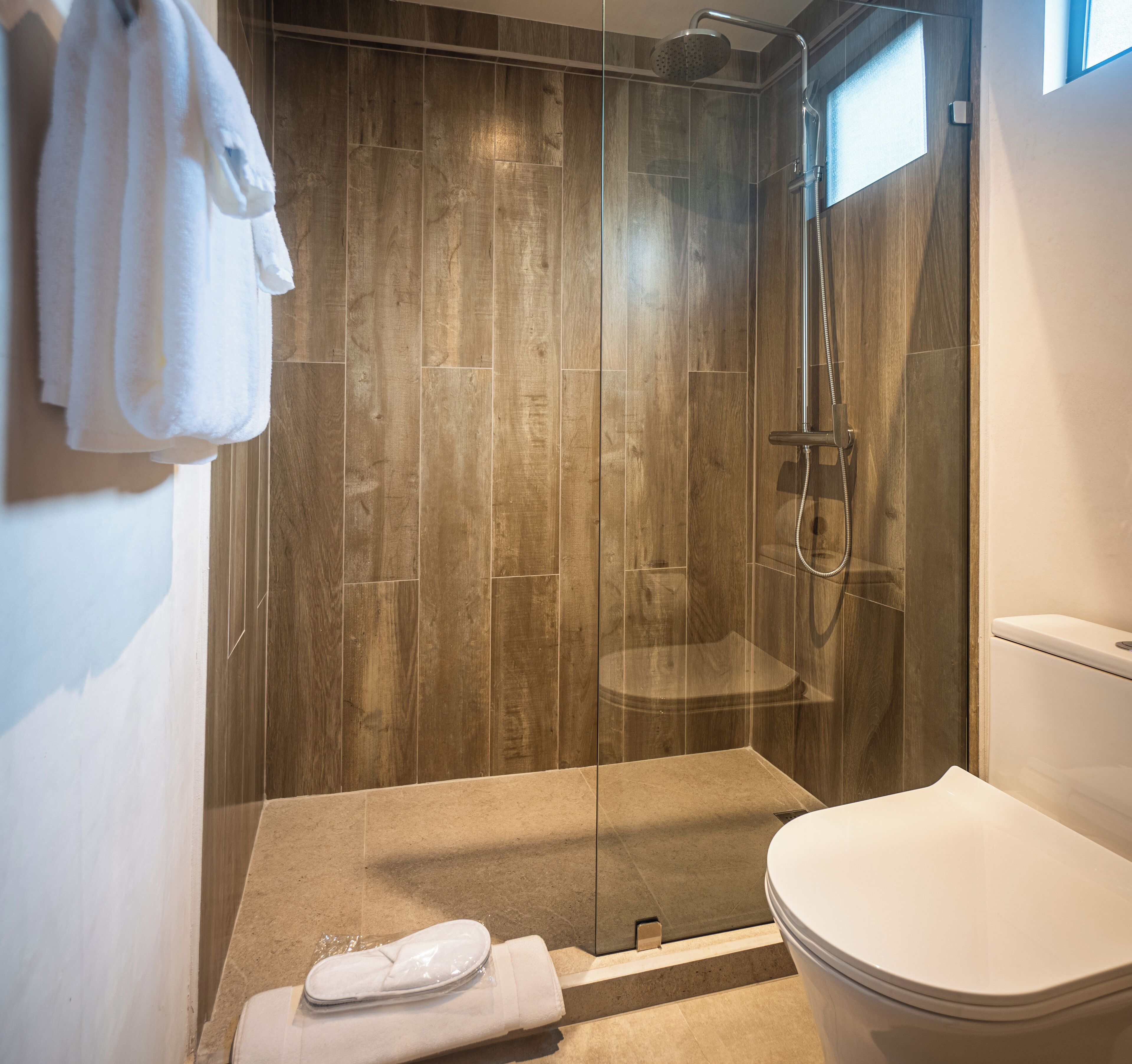 Een moderne badkamer met een douchecabine van glas, een toilet en een handdoekrek met handdoeken.
