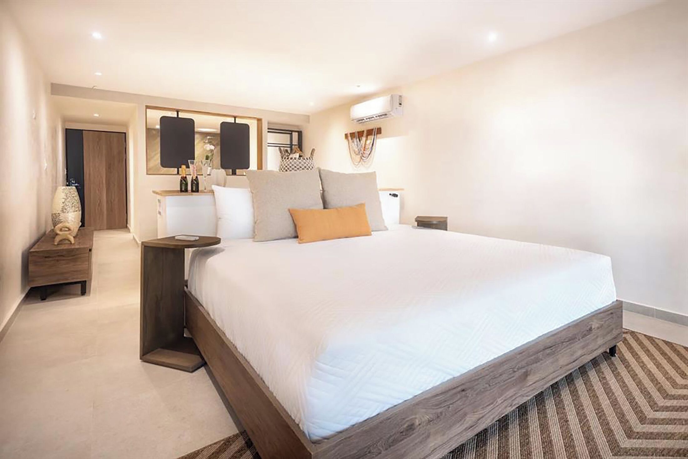 A modern bedroom with a large bed, bedside tables, a dresser, and a mirror.