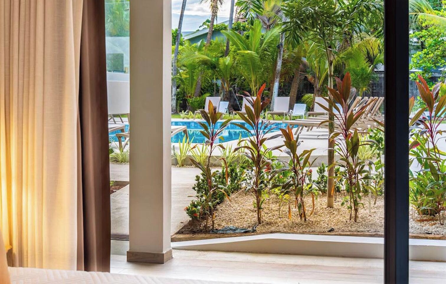 A view of a pool area with lounge chairs and tropical plants.