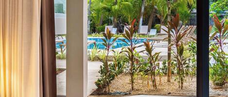A view of a pool area with lounge chairs and tropical plants.