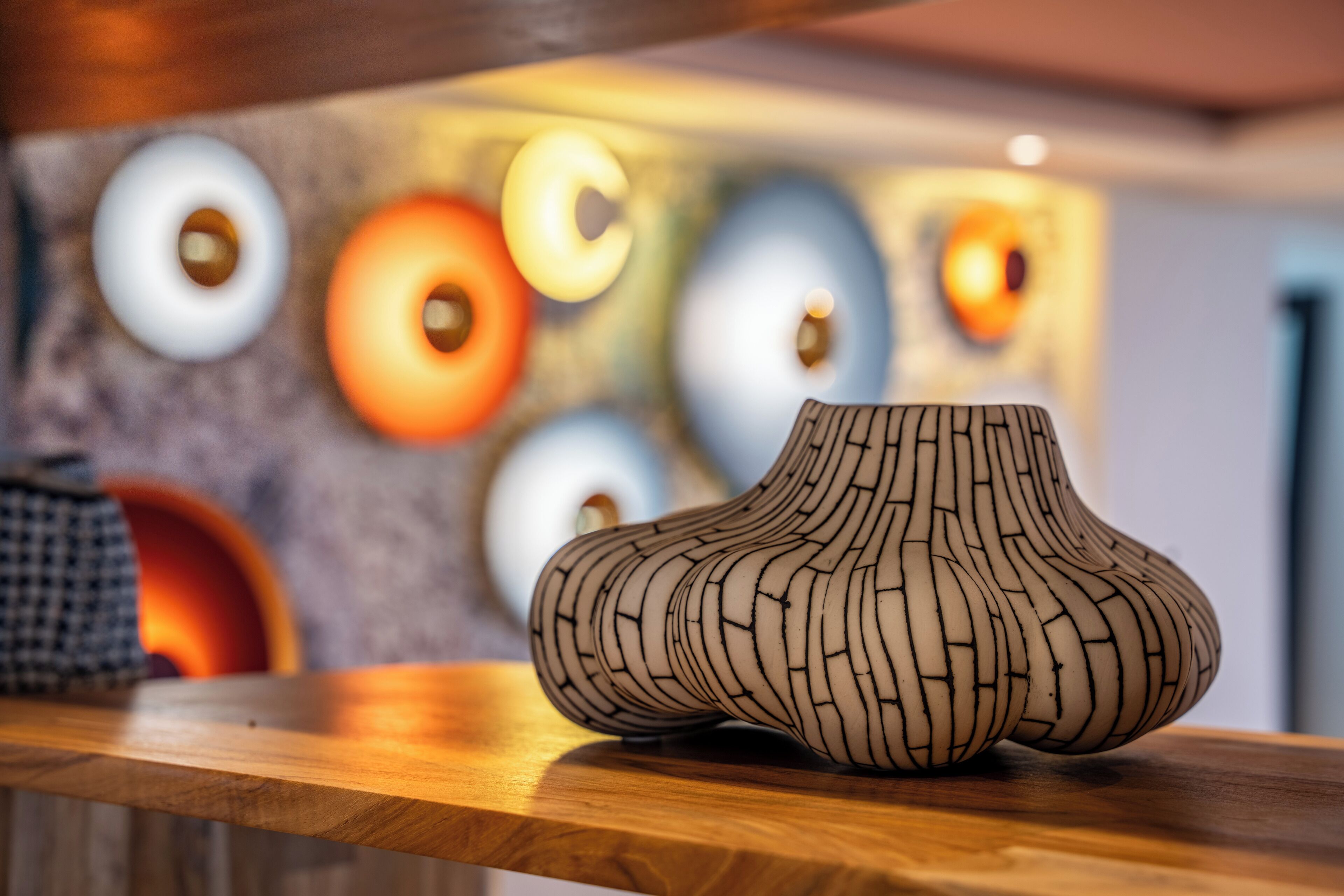 A wooden table with a unique, textured vase.