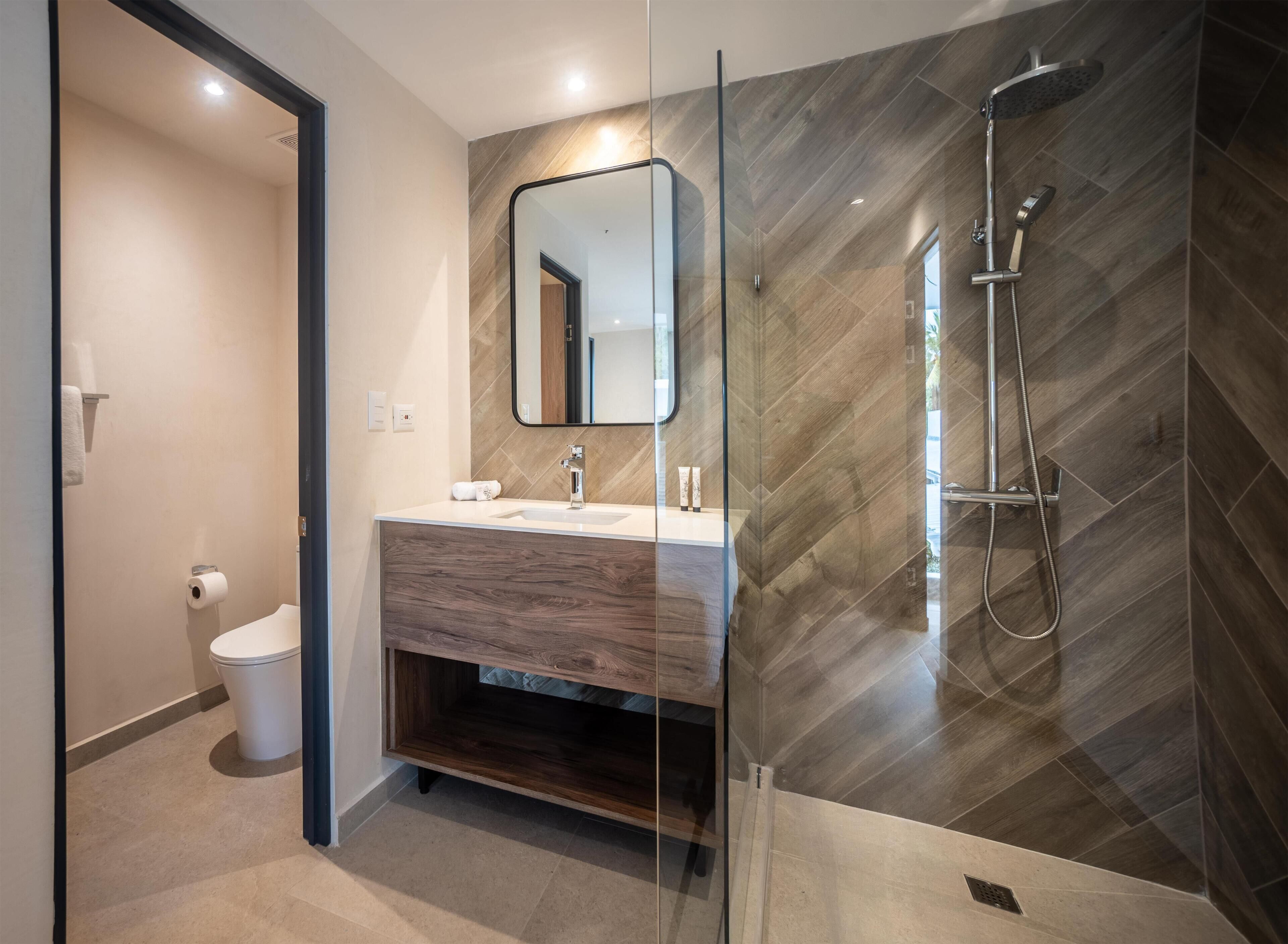 A modern bathroom with a glass-enclosed shower, a wooden vanity, and a toilet.