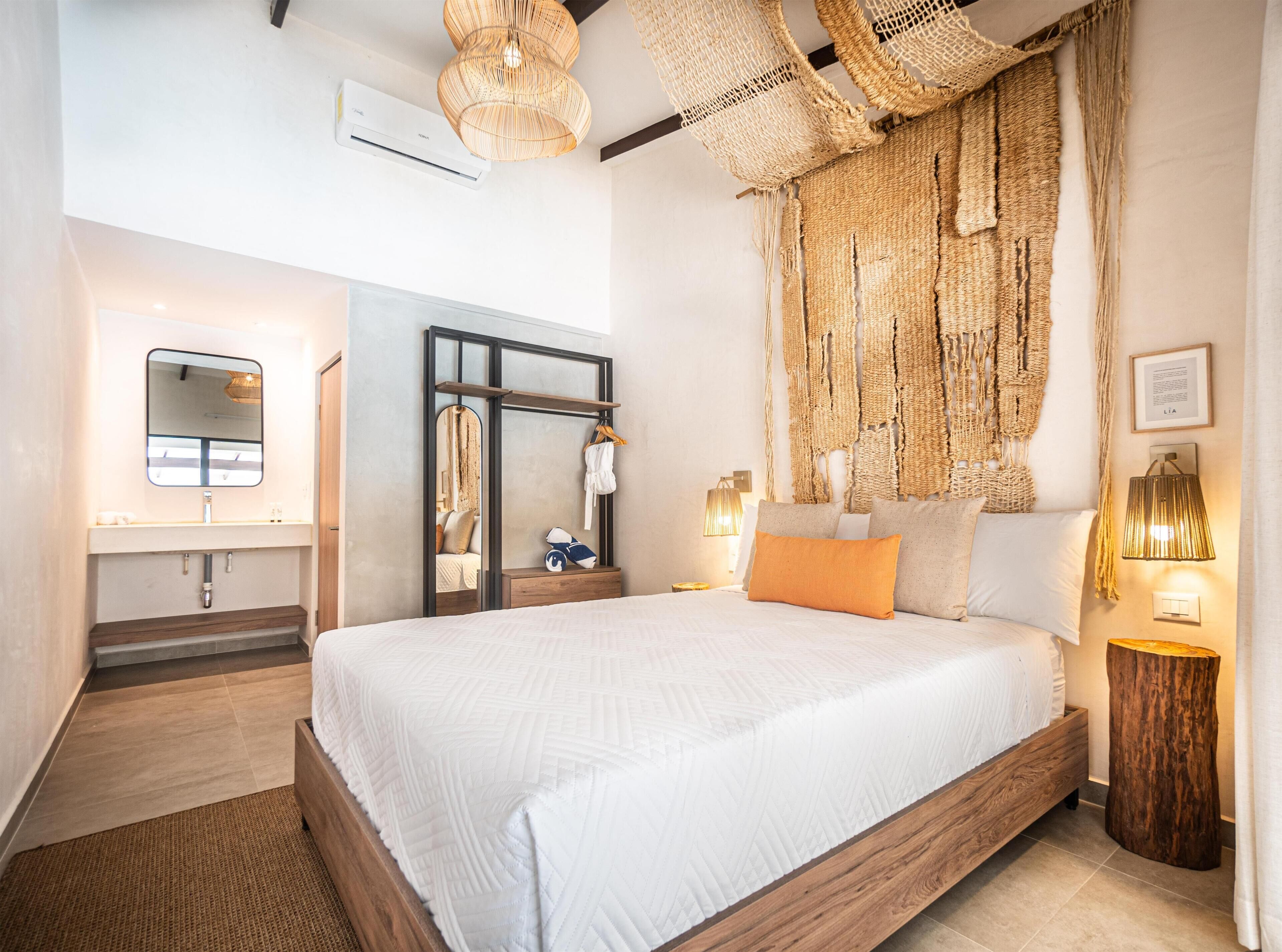 A modern bedroom with a large bed, a mirror, a wardrobe, and a wall-mounted air conditioner.