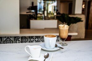 Une table avec une tasse de café et un verre de café glacé surmonté de crème fouettée.
