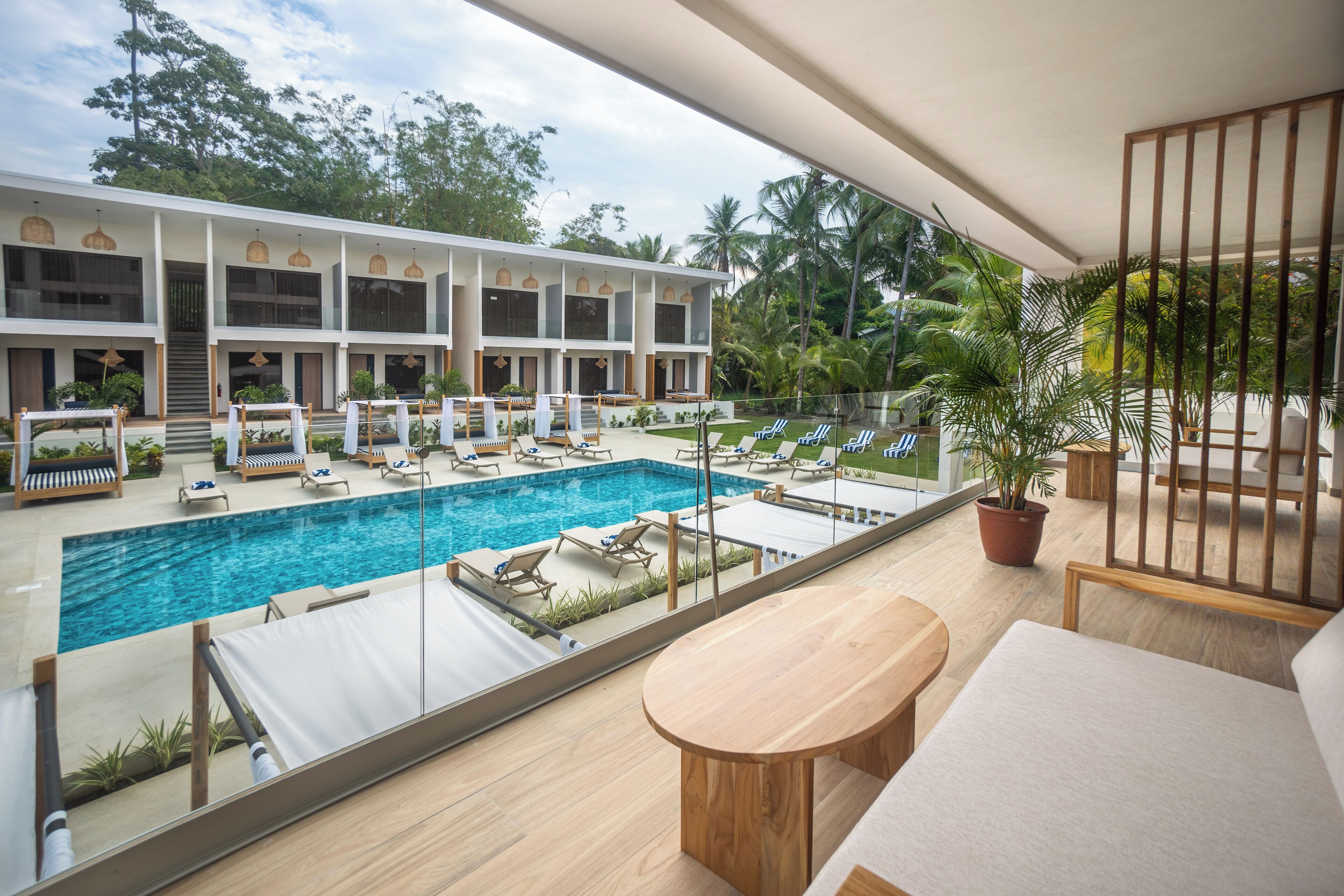 A hotel with a swimming pool, lounge chairs, and a view of the surrounding greenery.