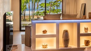 Une chambre moderne dotée d’une grande fenêtre donnant sur une plage, d’un comptoir d’accueil en bois et d’une collection de vases décoratifs.