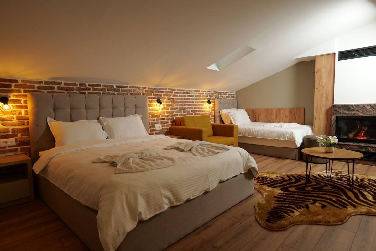 A bedroom with a brick wall, two beds, a fireplace, and a zebra rug.