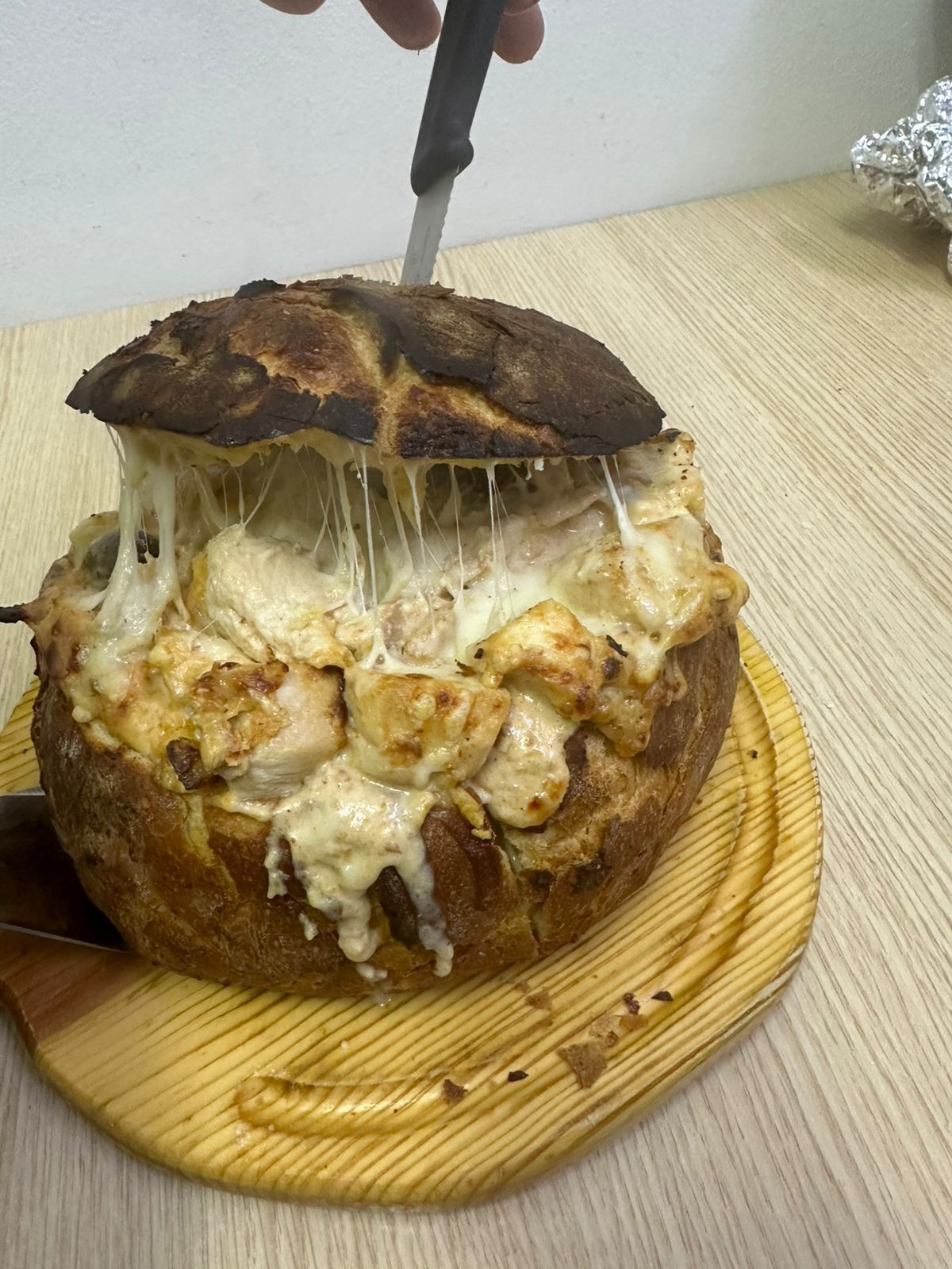 En limpa bröd med smält ost som skärs upp med en kniv.