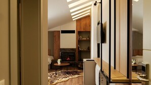 A modern interior with a wooden floor, a fireplace, a dining area, and a kitchen with a built-in refrigerator. - Vila Muslli (Korçë)