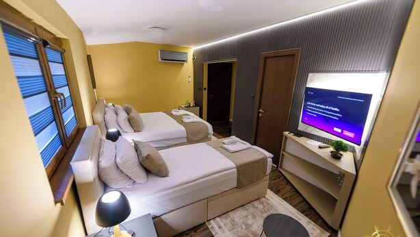Une chambre d’hôtel avec deux lits, un bureau avec une lampe, une télévision et une porte.