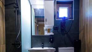 Une petite salle de bain comprenant une douche, des toilettes et un lavabo.