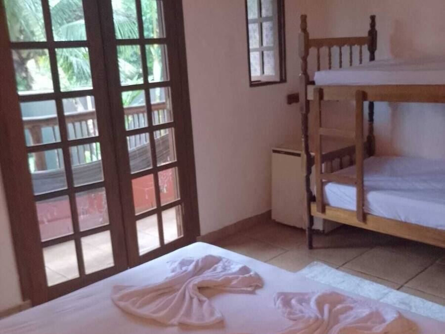 A room with a bunk bed, a small desk, a television, and a sliding glass door leading to a balcony.
