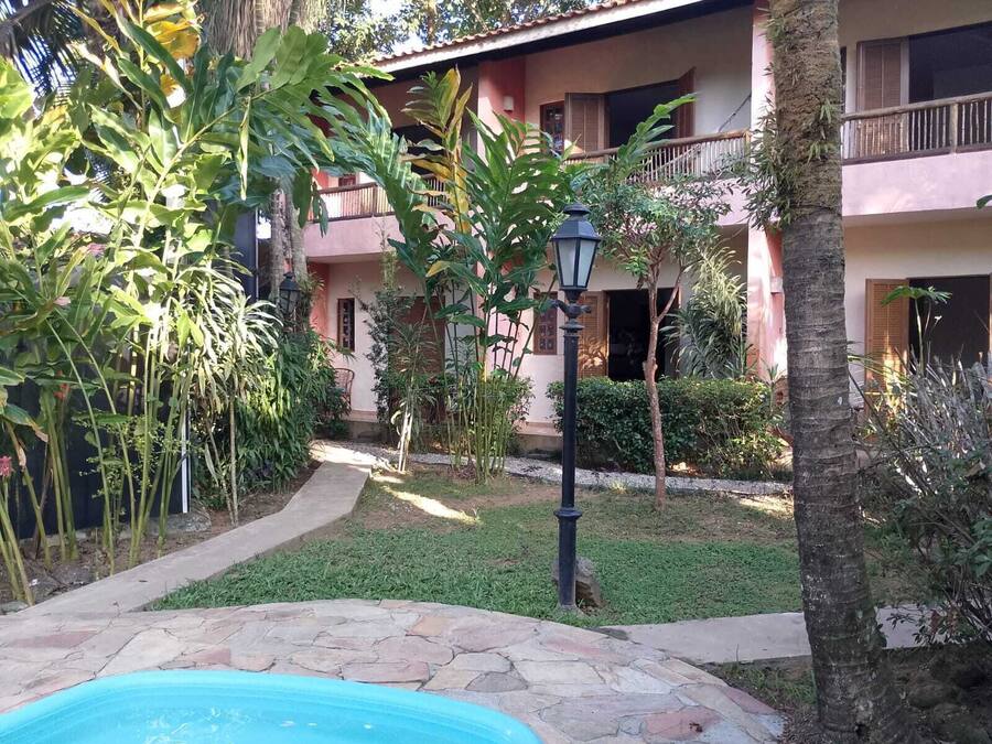 Un patio con piscina, rodeado de abundante vegetación y un edificio con balcones.