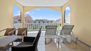 A covered balcony with wicker furniture and a view of buildings. - Amazing apartment in Vodice with WiFi (Vodice)