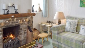 A cozy living room with a fireplace, a chessboard, a sofa, and a neon sign that reads "Love". - 2 bedroom accommodation in Brandesburton (Brandesburton)