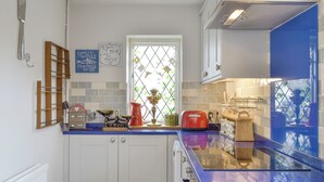 A kitchen with white cabinets, a blue countertop, and a window with a view of greenery. - 2 bedroom accommodation in Brandesburton (Brandesburton)