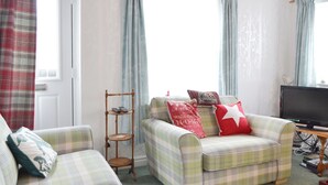 A living room with two plaid sofas, a small wooden side table, and a television. - 2 bedroom accommodation in Brandesburton (Brandesburton)