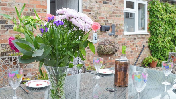 A table set with a vase of flowers, wine glasses, and a bottle. - 2 bedroom accommodation in Brandesburton (Brandesburton)