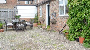 A brick house with a gravel patio, outdoor seating, and potted plants. - 2 bedroom accommodation in Brandesburton (Brandesburton)