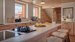 A modern kitchen with a central island, wooden cabinets, and a large window.