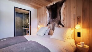 A bedroom with a large bed, wooden walls, and a mounted fur rug.