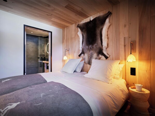 Ein Schlafzimmer mit einem großen Bett, Holzwänden und einem Fellteppich an der Wand.