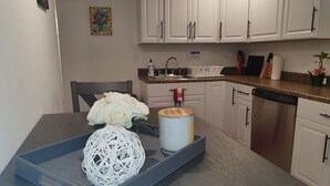 Eine moderne Küche mit weißen Schränken, einer Granit Arbeitsplatte, einem Spülbecken und einem Geschirrspüler.