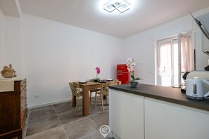 A compact kitchen with a dining area, a red cabinet, and a window with curtains.