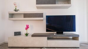 Un soggiorno moderno con una televisione a schermo piatto, scaffali a parete e un design minimalista.