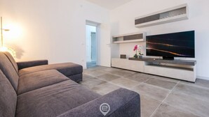 Un soggiorno moderno con un'ampia televisione a schermo piatto, divani grigi e un design minimalista.