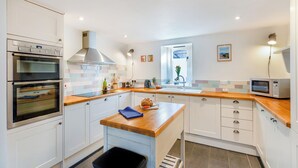 Une cuisine moderne dotée de deux fours, d’un îlot central et d’un four à micro-ondes.