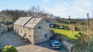 Un bâtiment en pierre avec une voiture garée devant, entouré d’un paysage rural.