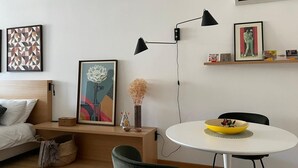 A modern living room with a bed, a round dining table, and a green chair.