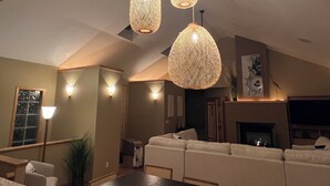 Un salon avec un plafond haut, un ensemble de canapés et une cheminée.